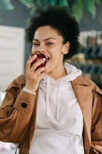 Woman biting into an apple with porcelain veneers after treatment in Thornhill