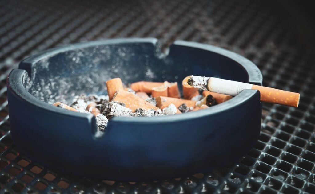 Ashtray with a cigarette illustrating smoking risks for dental implants