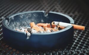Ashtray with a cigarette illustrating smoking risks for dental implants